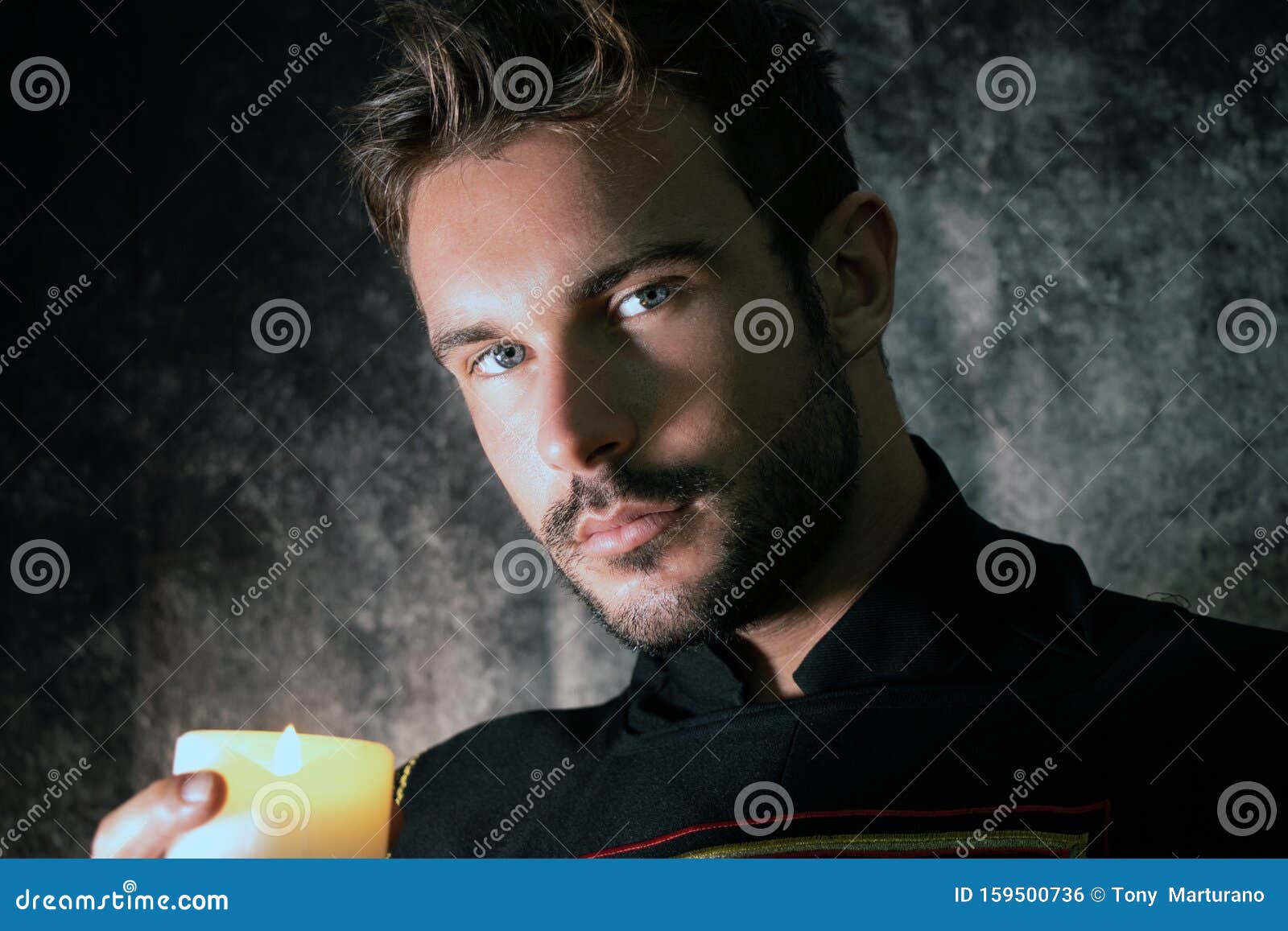 portrait of handsome medieval knight with beard and blue eyes, holding a candle and looking at camera