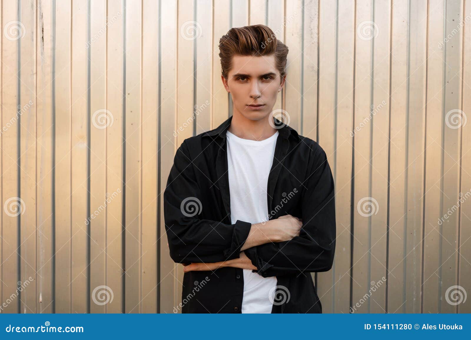 Handsome Modern Young Man with a Fashionable Hairstyle in an Elegant Black  Shirt in a T-shirt Poses Near a Silver Wall in the City Stock Photo - Image  of shirt, european: 154111280