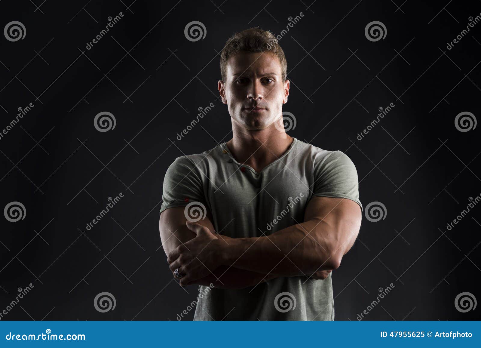 handsome muscular fit young man on dark background with stern expression