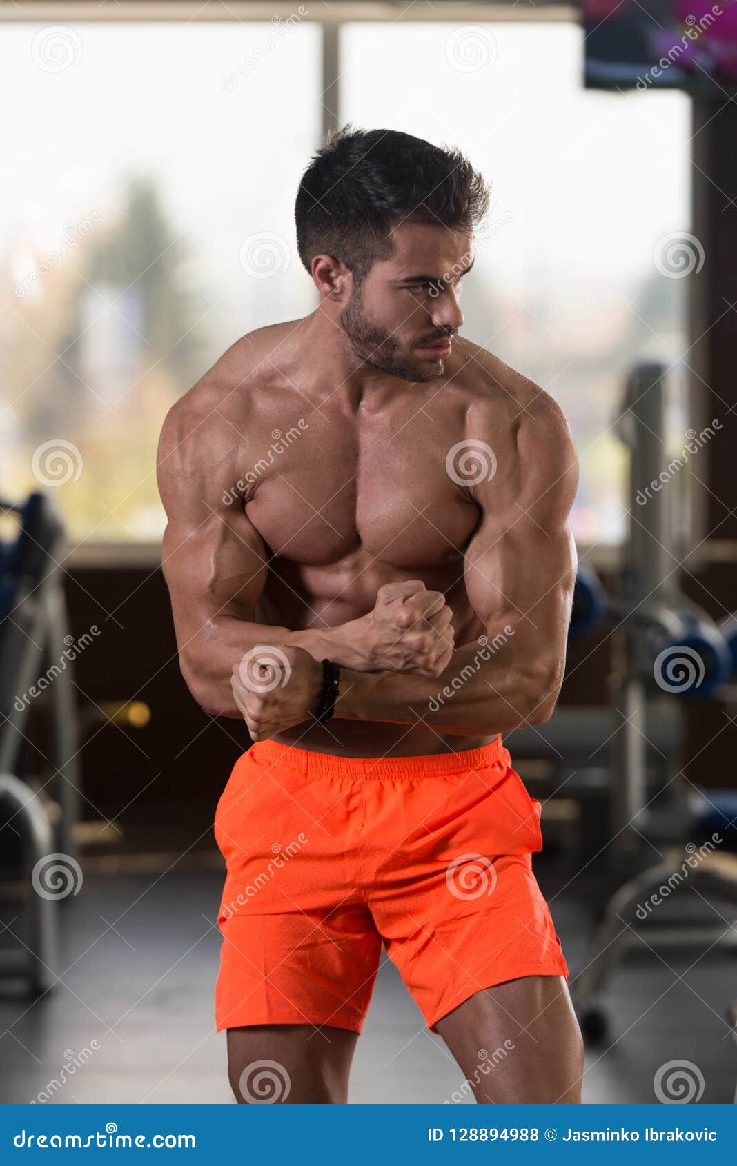 Athletic man with a muscular body poses in the gym 
