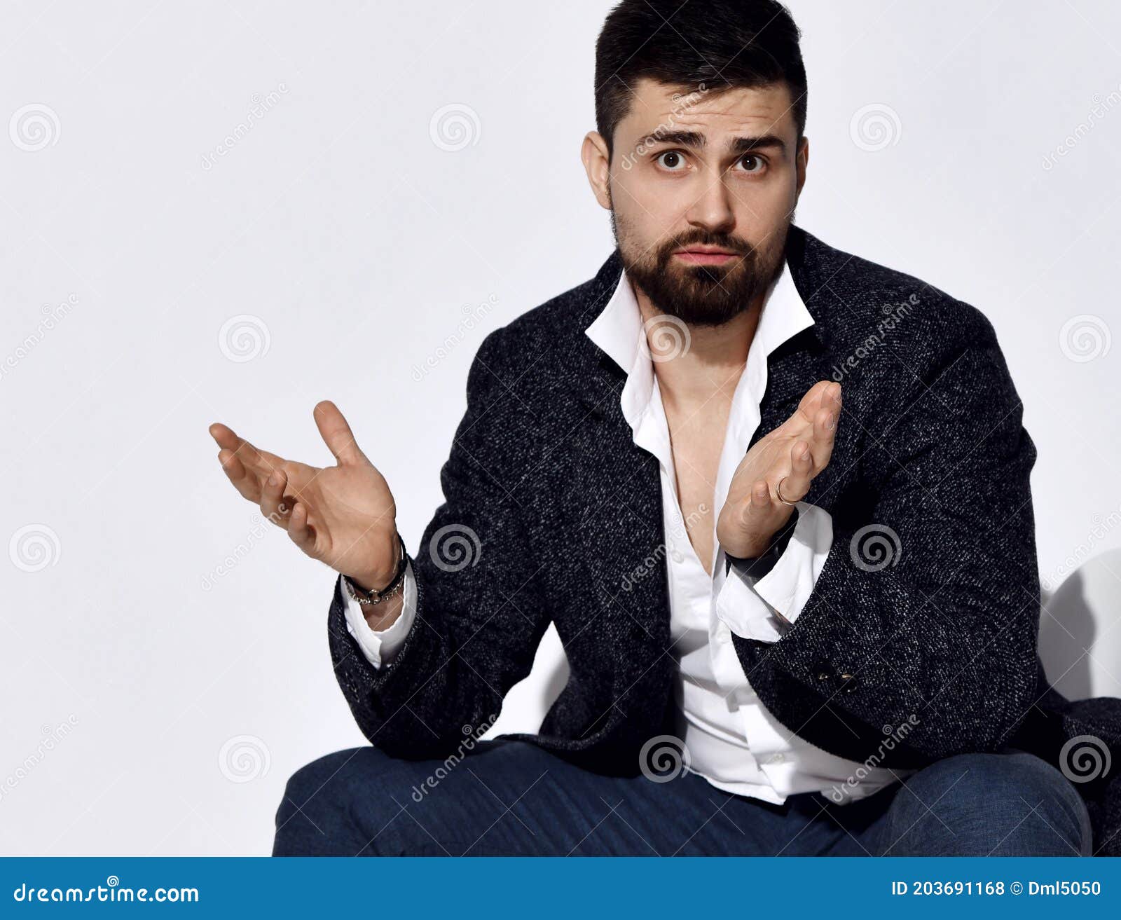 handsome serious brunette brutal businessman in stylish official suit and shirt sitting and gesticulating during communication