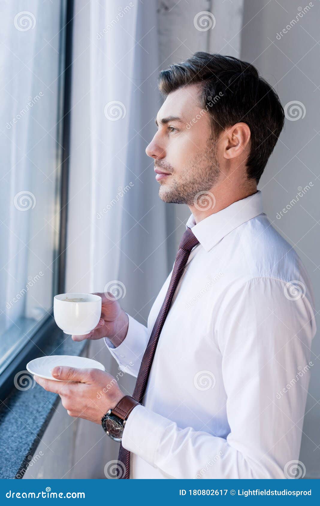 Handsome Serious Man with Coffee Cup Standing by Window and Looking ...