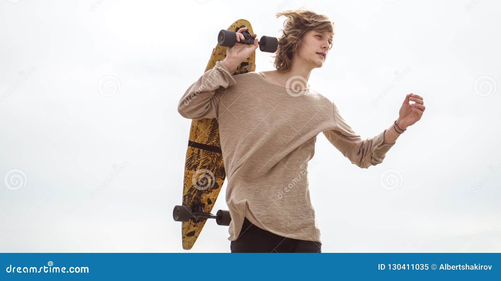 Man Standing with Skateboard on His Shoulder and Looking Aside Stock ...