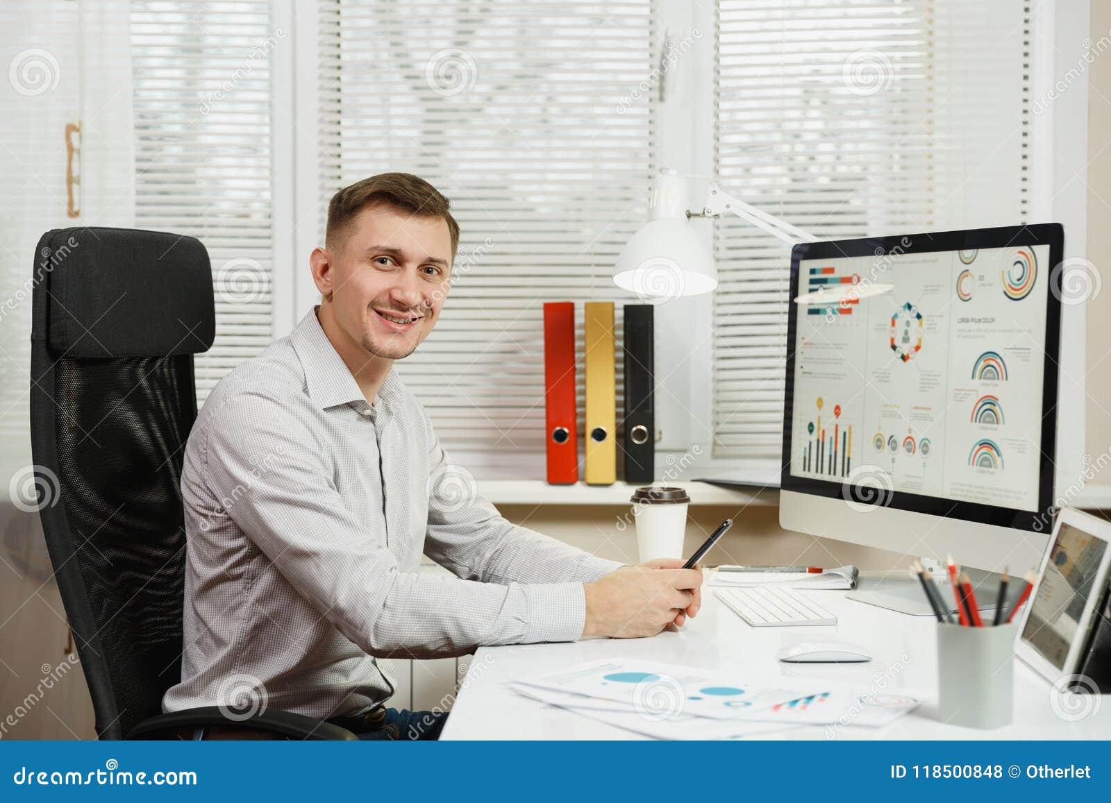 serious and engrossed business man in shirt sitting at the desk, working at computer with modern monitor. manager or worker.