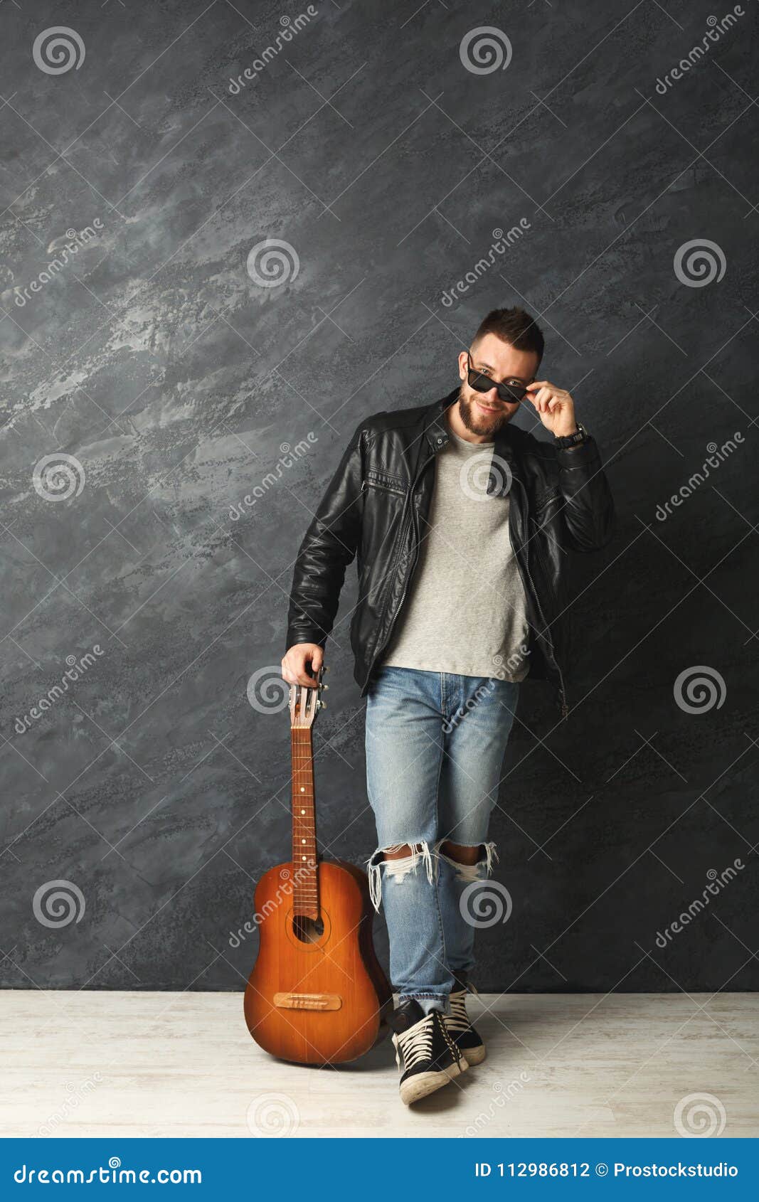 Studio Portrait From Below Upward Of Young Guitarist Pose With Leg Up,  Holding Guitar While Looking Away Stock Photo, Picture and Royalty Free  Image. Image 51844317.