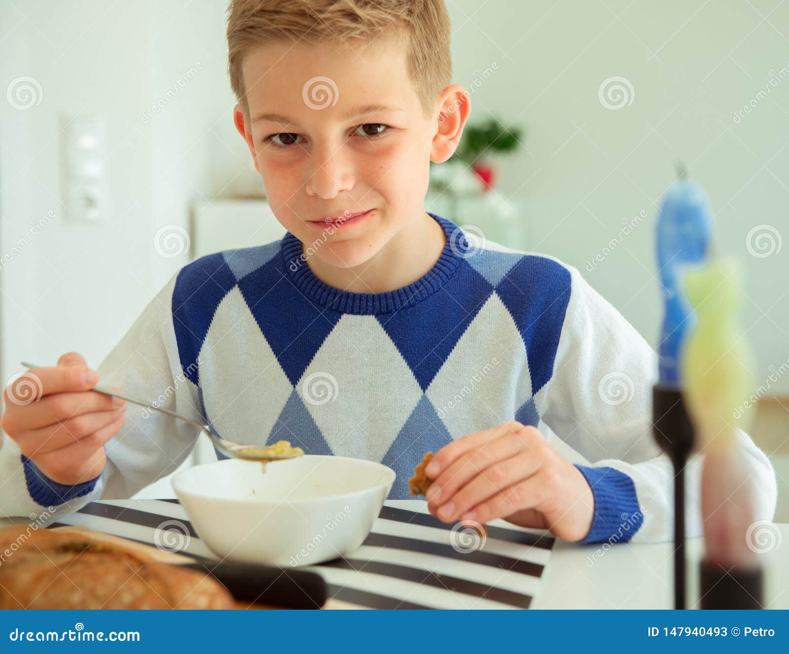 Handsome Teenager Eating Soup And Whole Grain Bread In Bright