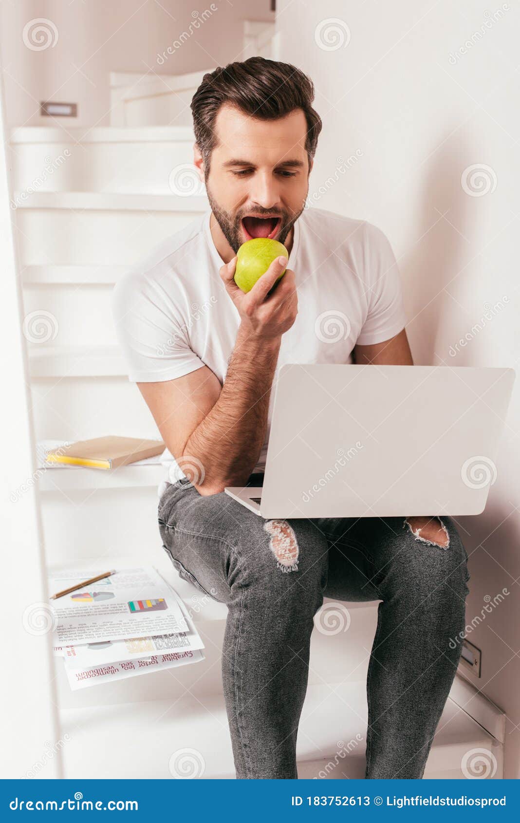 handsome teleworker eating apple while working