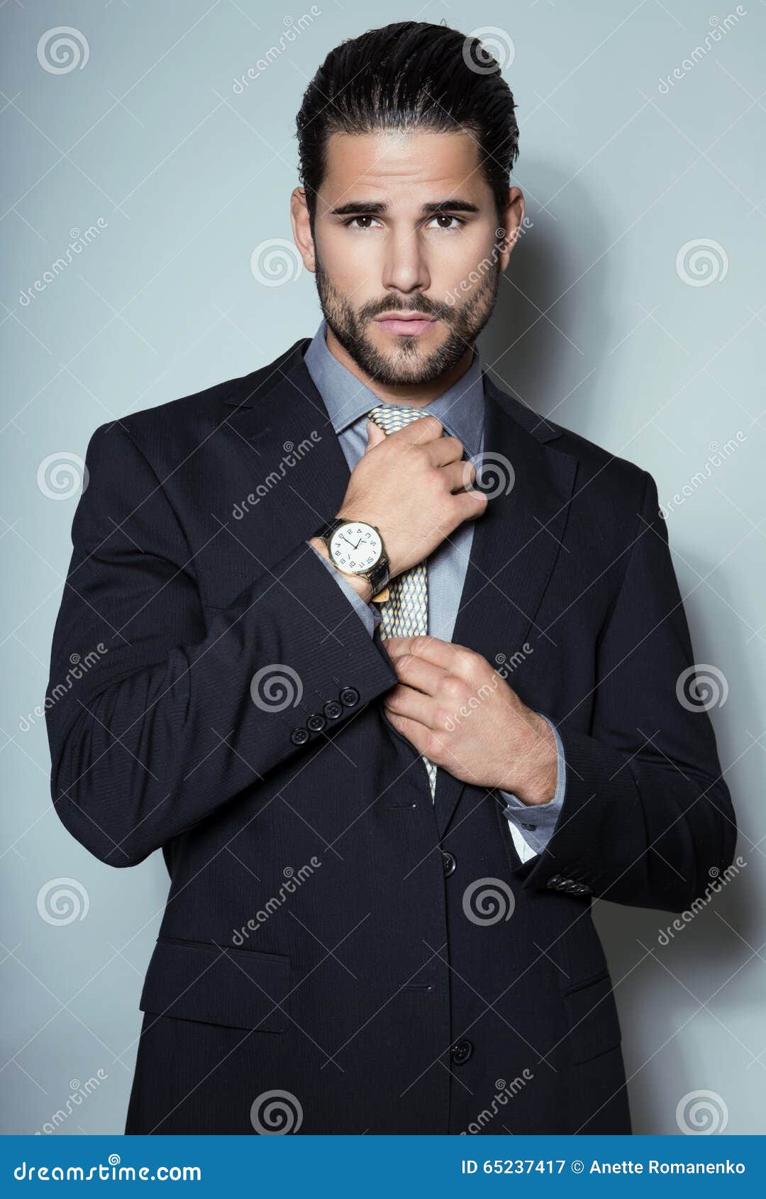 handsome young business man in suit on grey background