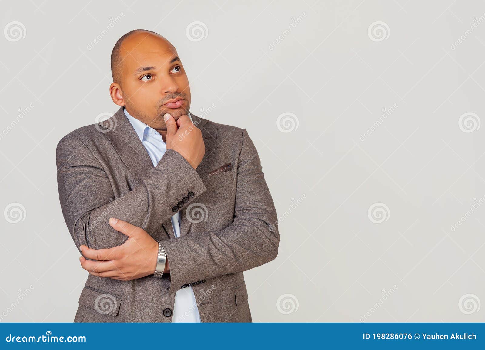 handsome young male african american businessman in jacket looking to the side and thinking touching chin with hand