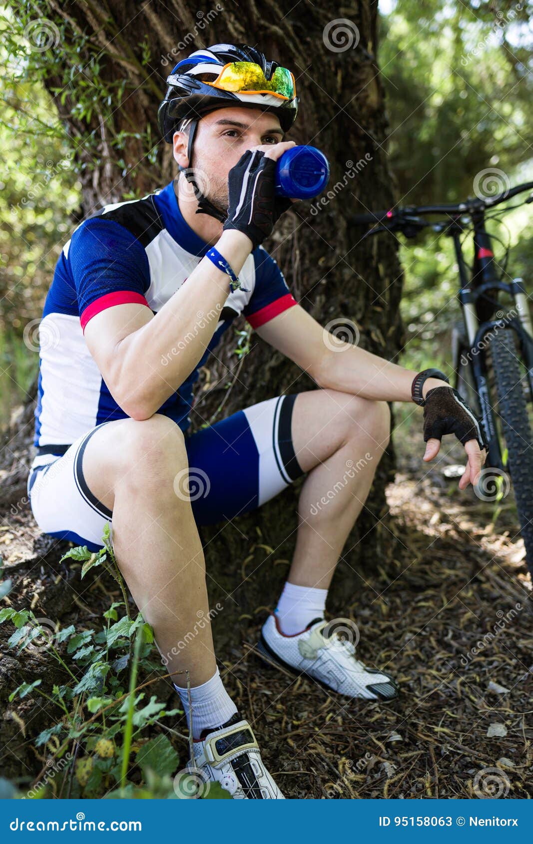 handsome young man drinking water after cycling in the mountain.