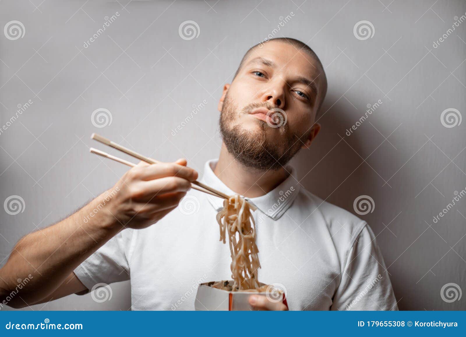 Handsome Young Man Eats Noodles from Food Delivery on a White ...