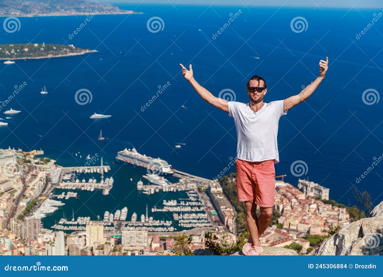 a handsome young man stands and jubilantly with his hands raised on a mountain with the name of a head of dog, the
