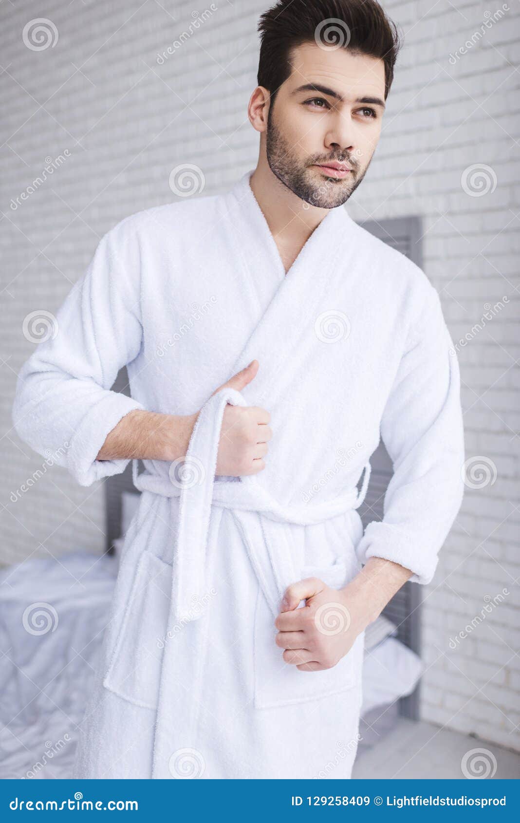 Handsome Young Man Tying Belt of Bathrobe and Looking Away Stock Image