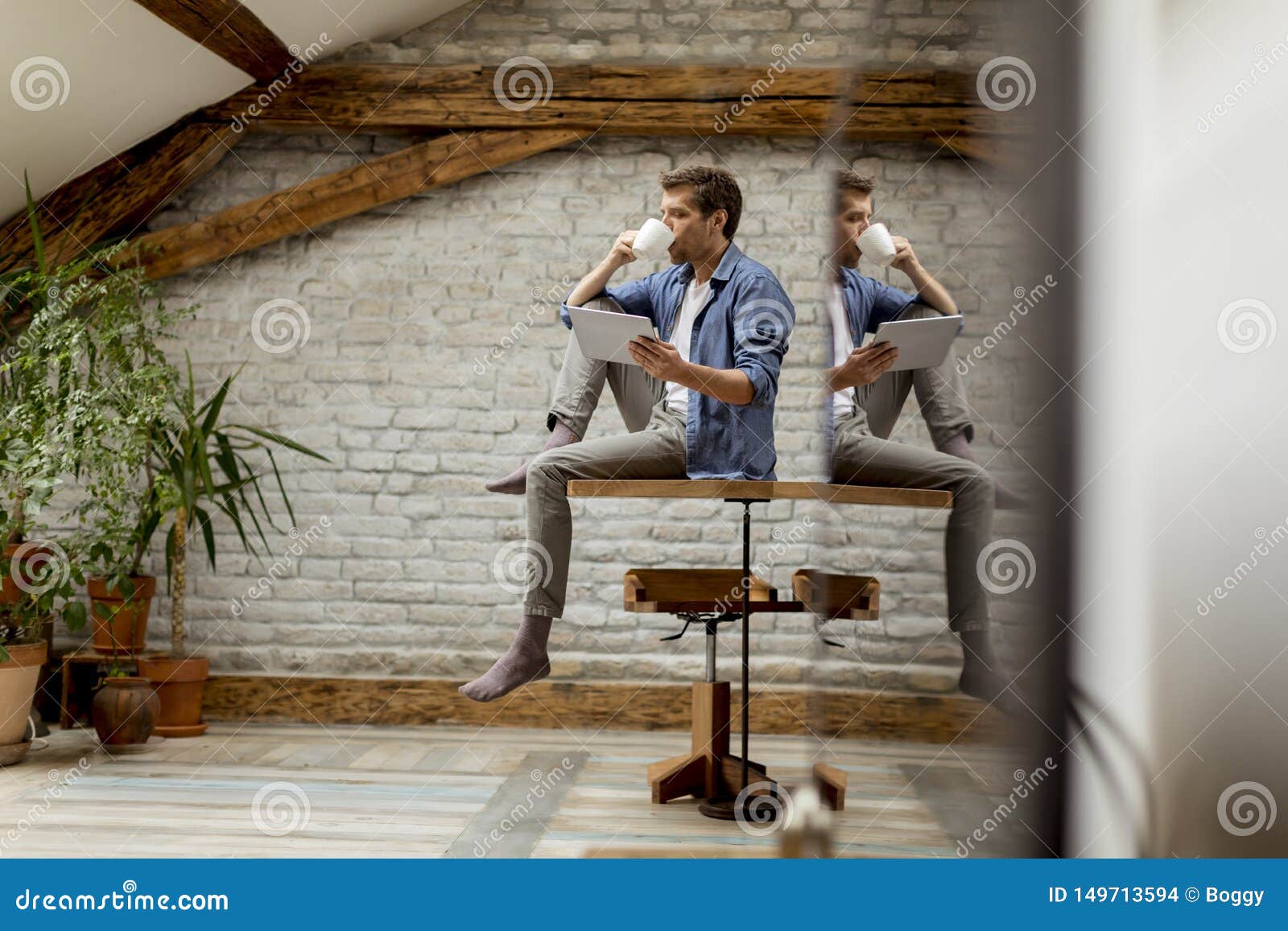 handsome young man using digital tablet and srinking coffee while sitting in the rustic room