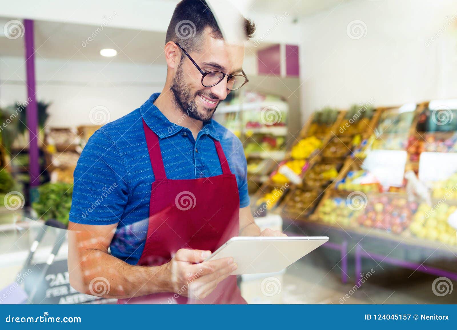 handsome young salesman using his digital tablet in health grocery shop.