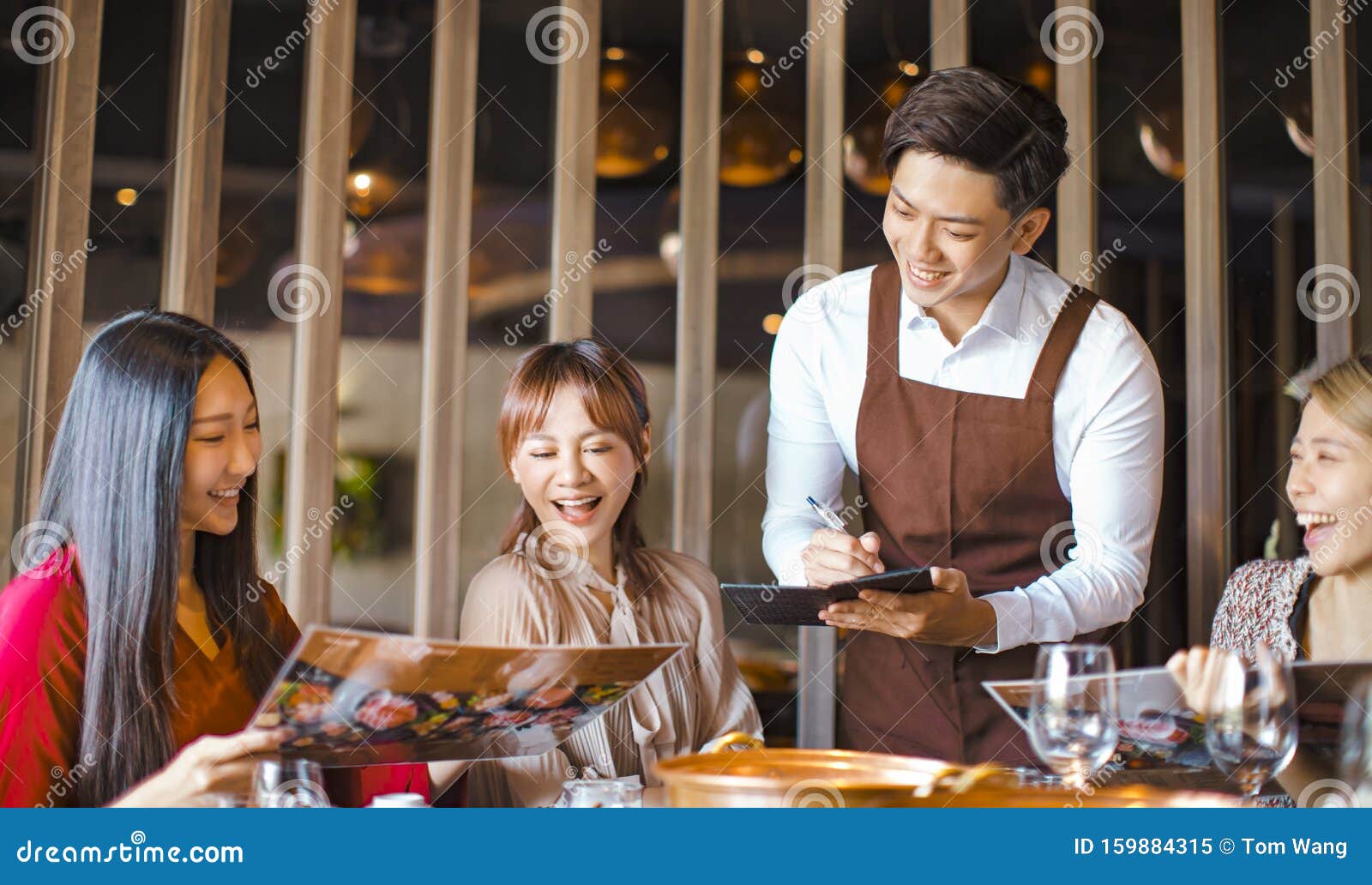 young waiter  taking an order  in hot pot reataurant