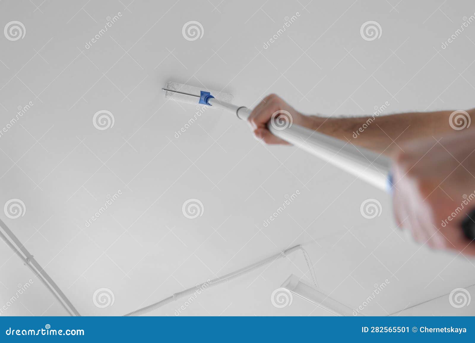 Handyman Painting Ceiling with Roller, Low Angle View Stock Image