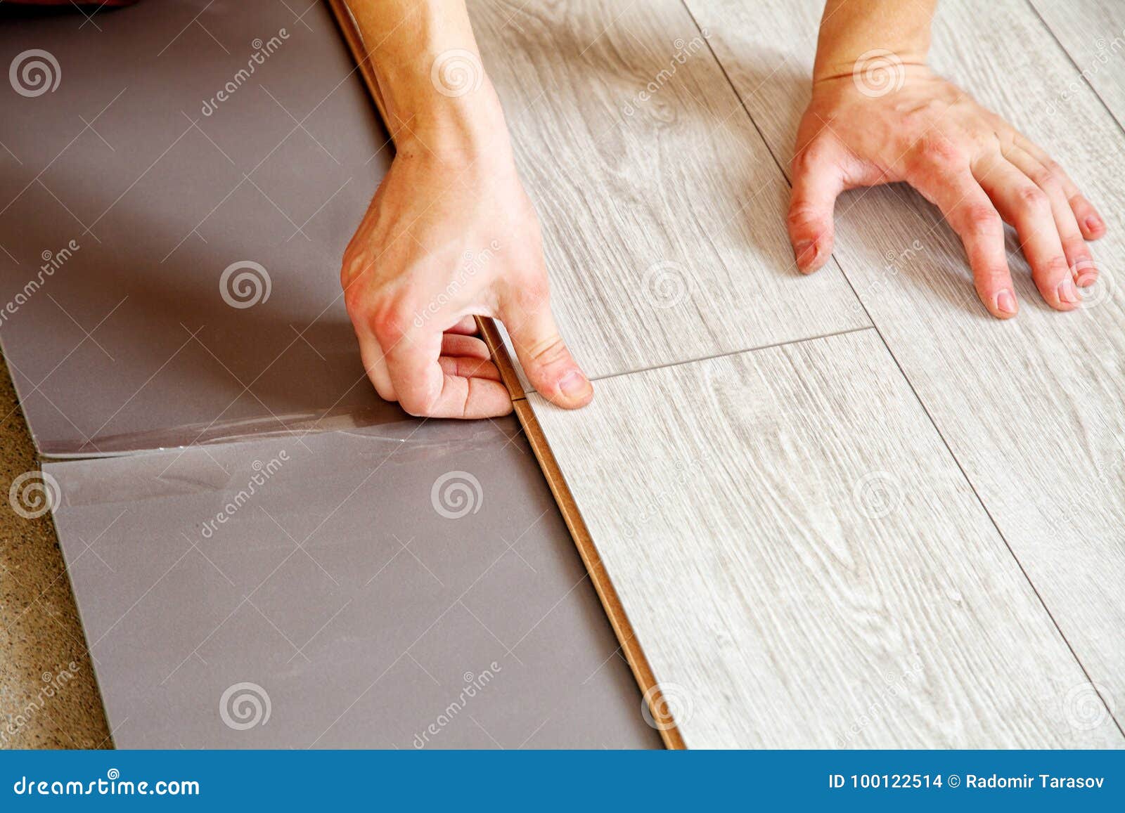 handyman`s hands laying down laminate flooring boards