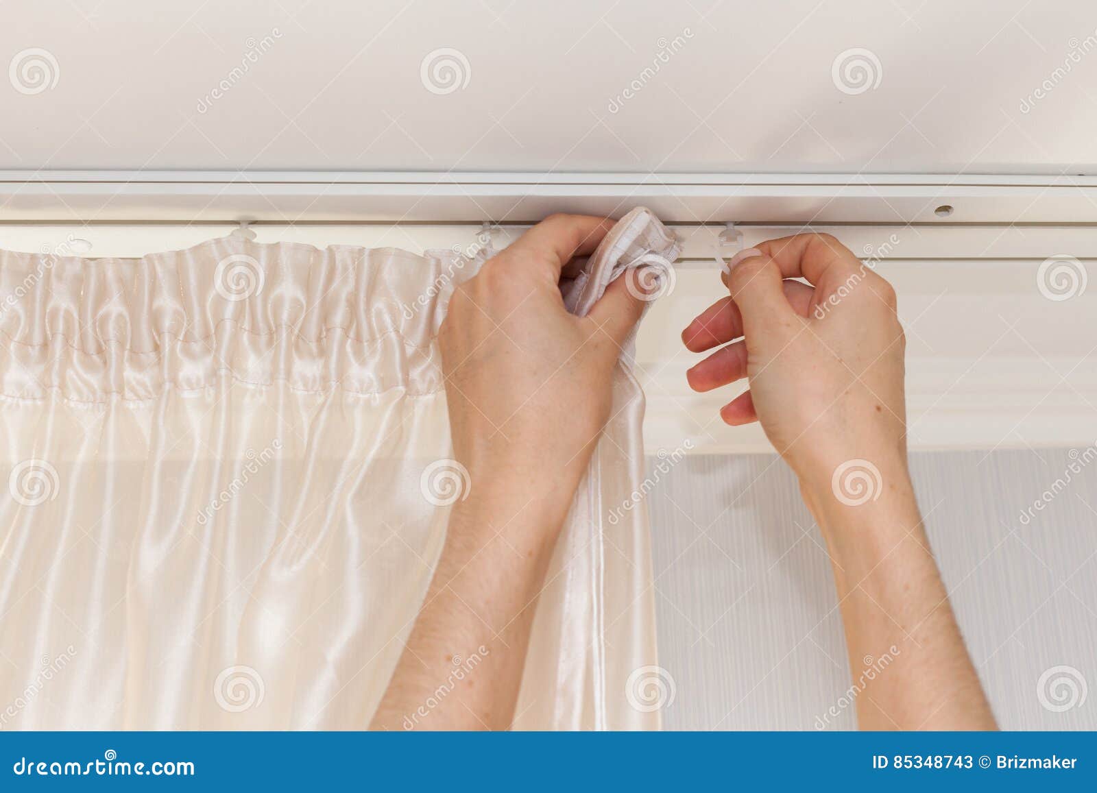 hanging up curtain using pleat hooks.