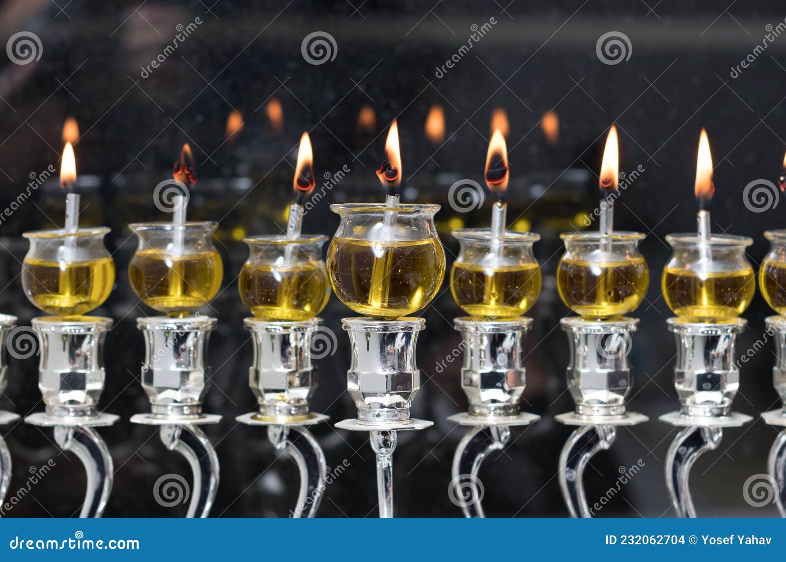 Hanukkah Candles are Lit in a Silver Menorah Against the Backdrop of