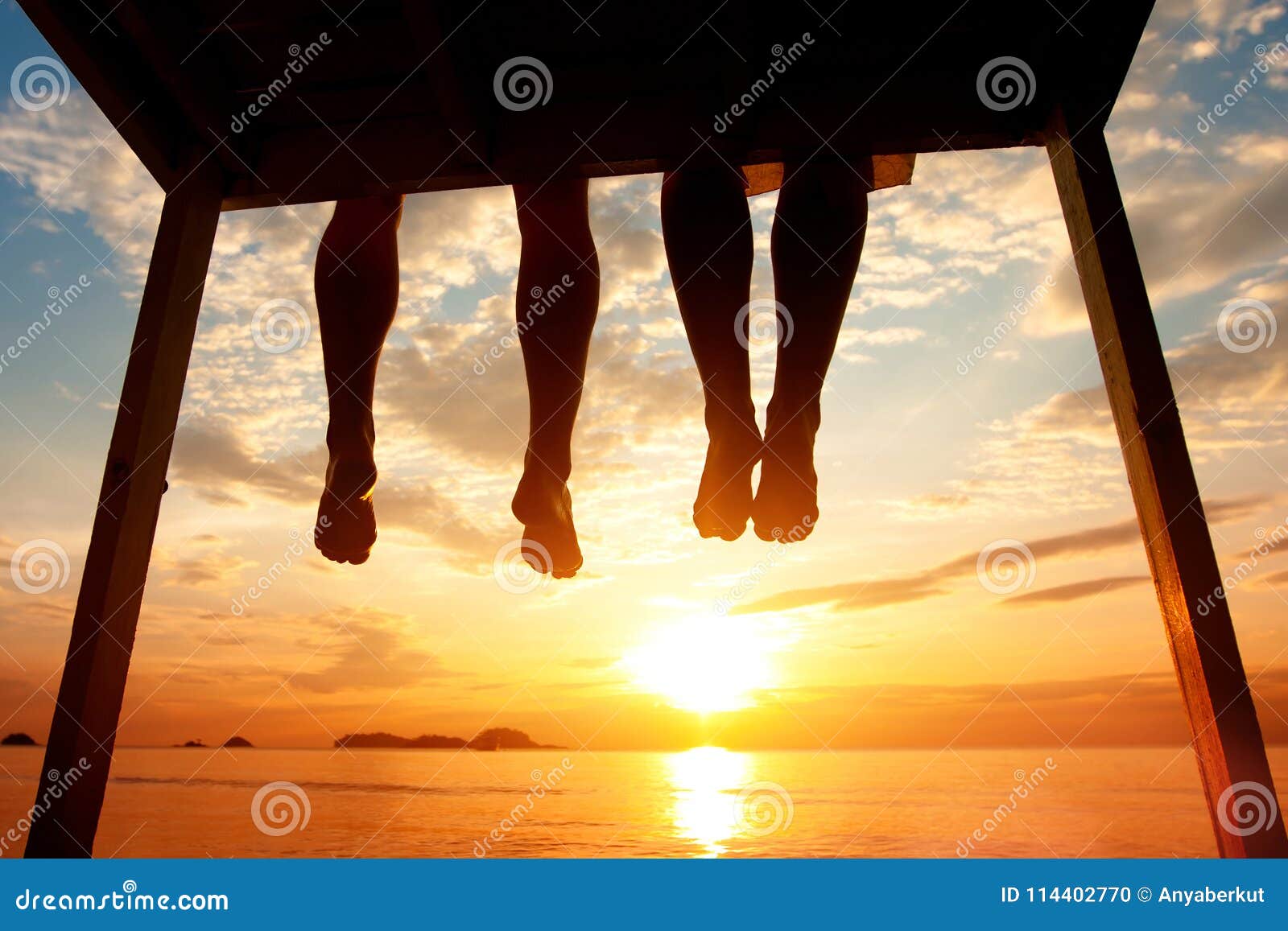 happiness concept, silhouette of feet of couple sitting on the pier on beach