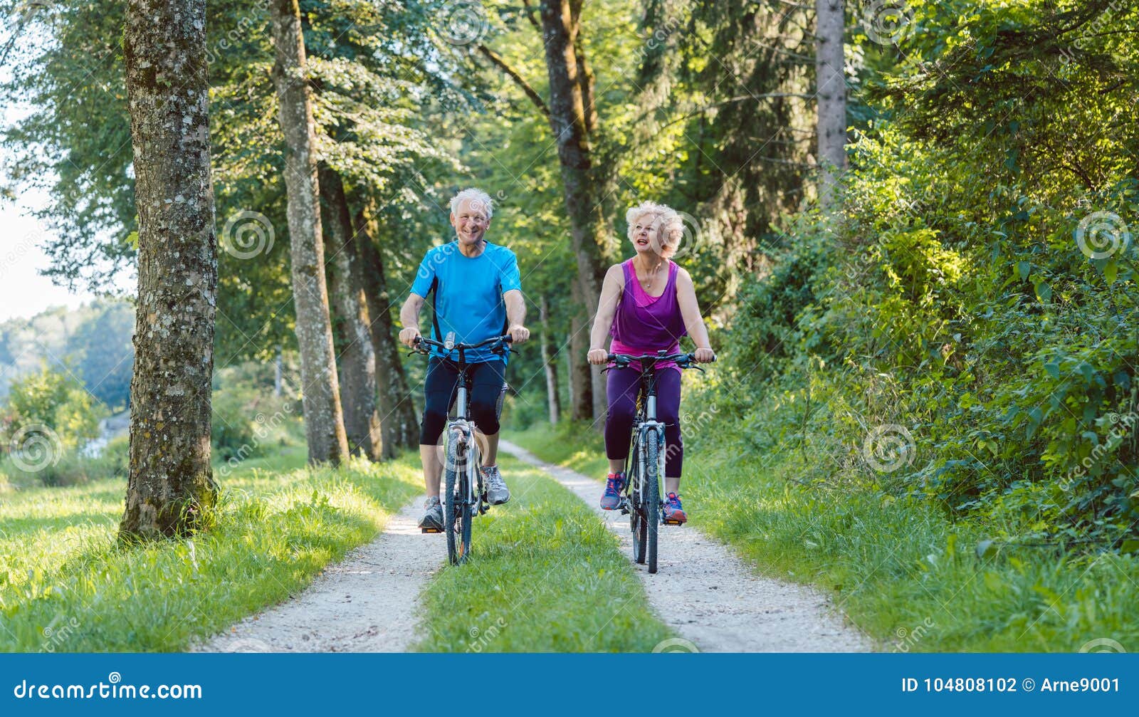 happy and active senior couple riding bicycles outdoors in the p