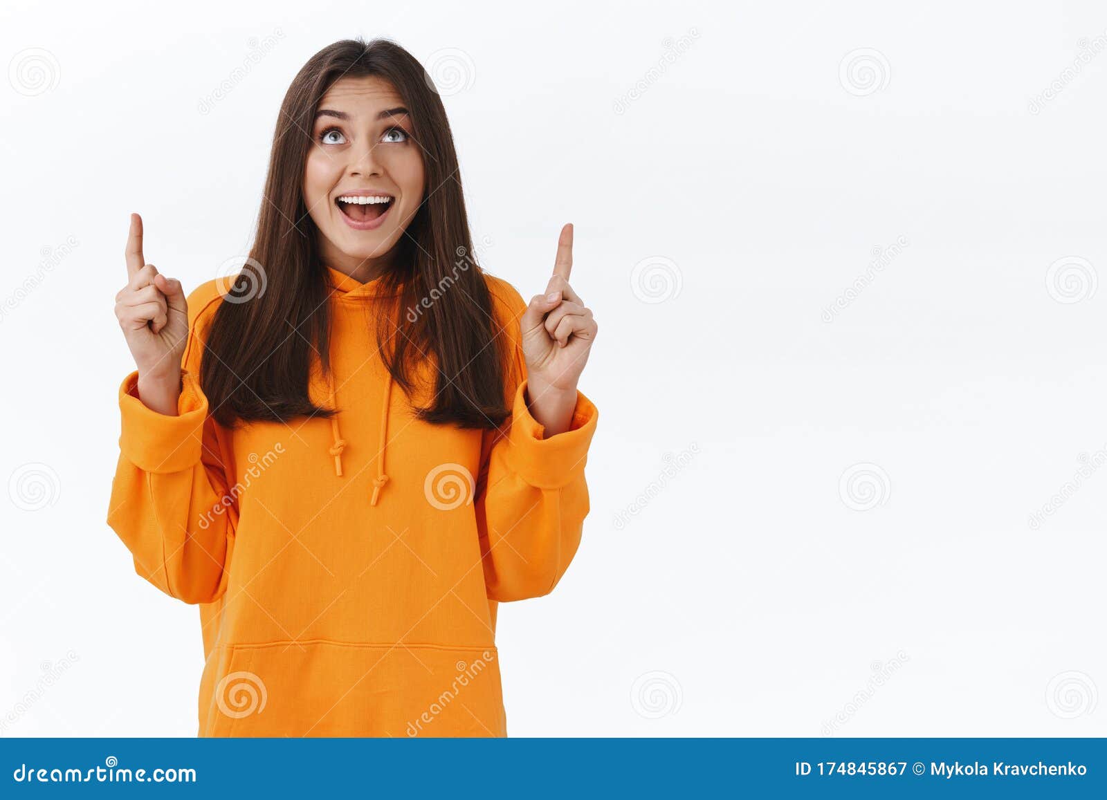 Happy Adorable Brunette Woman In Orange Hoodie Pointing And Looking Up