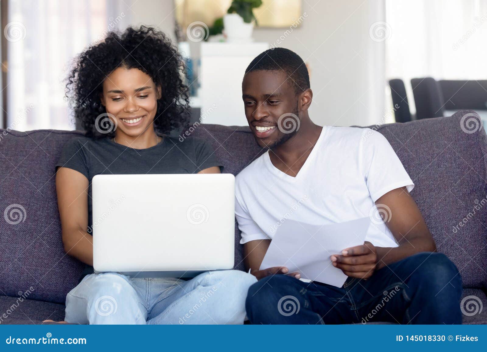 happy african american couple using laptop, receive good news