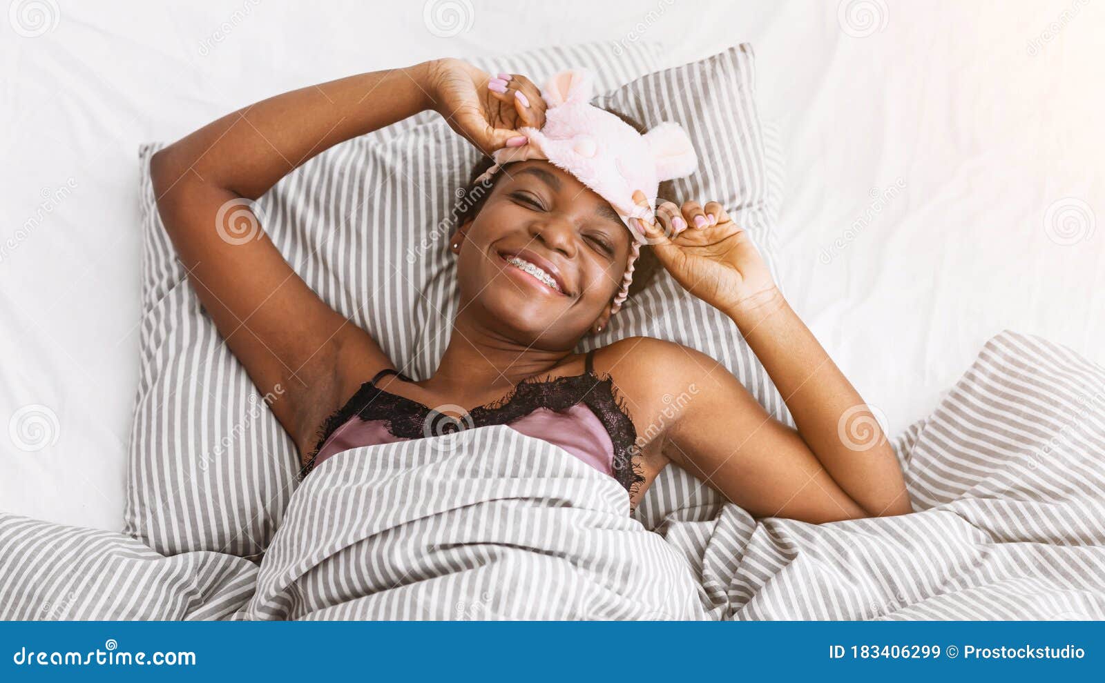 Happy African American Girl with Braces in Bed Takes Off Her