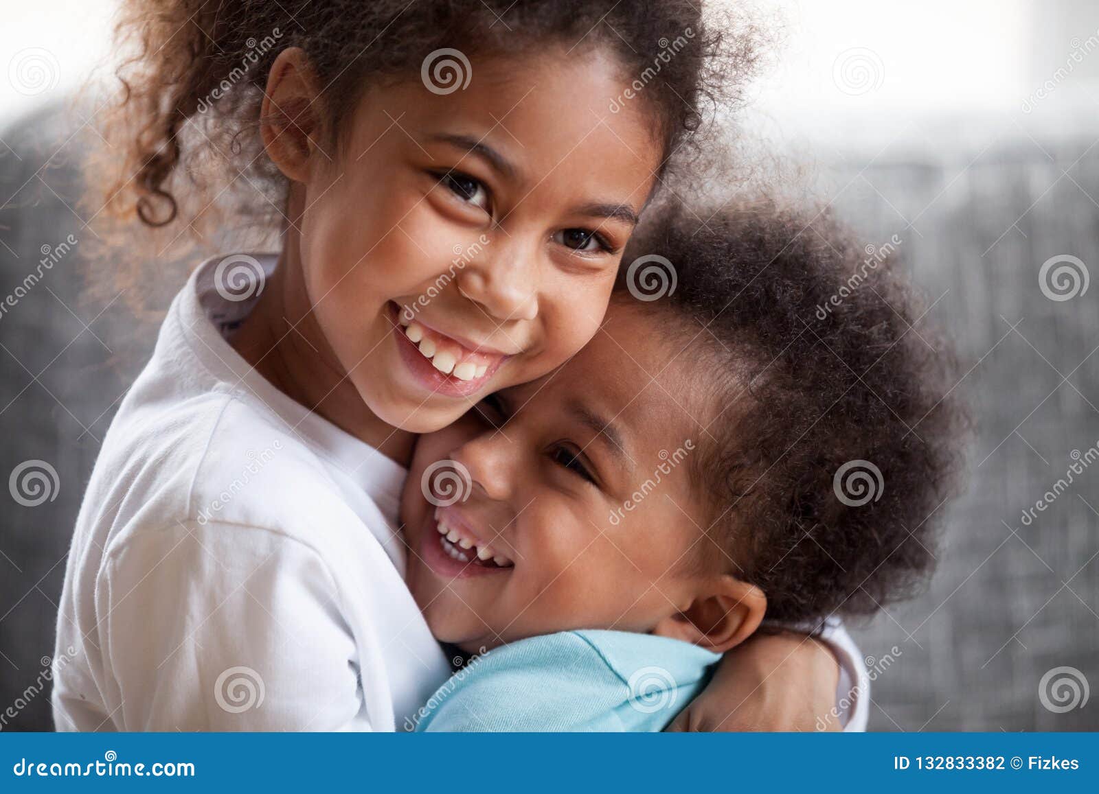 happy african american siblings embracing, sitting together