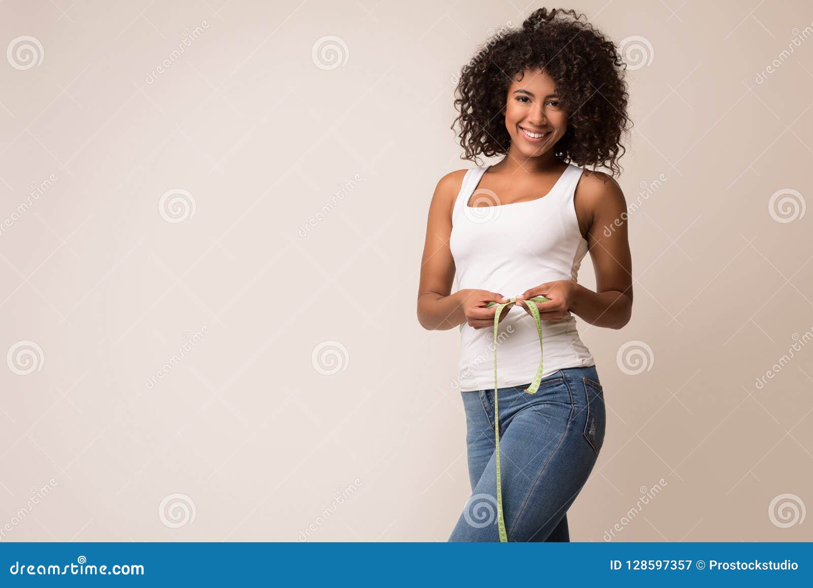 happy african-american woman measuring waist with tape