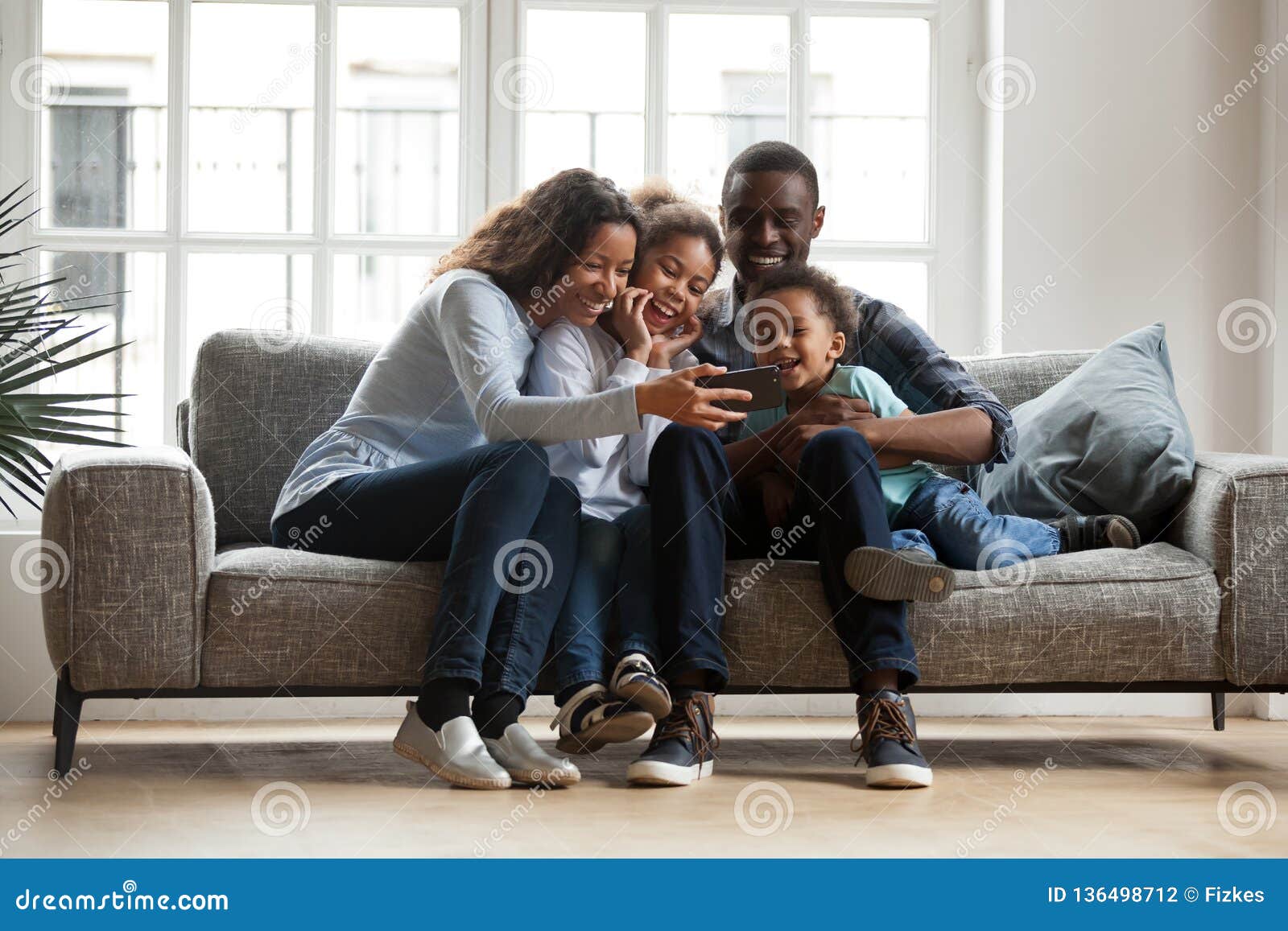 happy african family with 2 children having fun with gadget