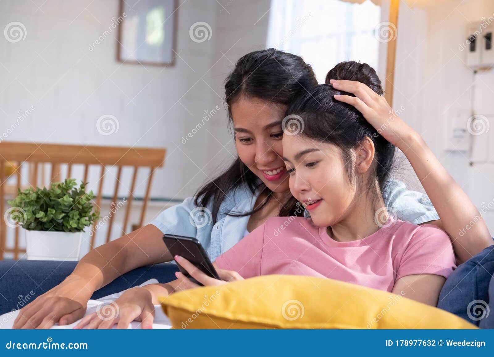 Happy Asian Lesbian Couple Using Mobile Phone Together At