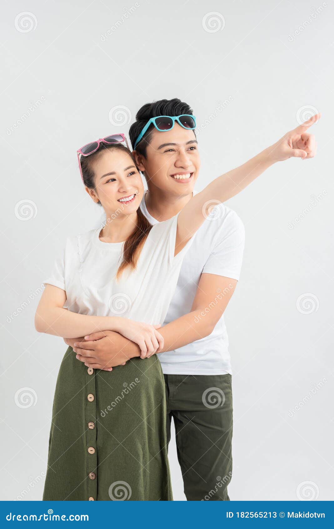 Happy Asian Man Hugging Smiling Girlfriend While Pointing