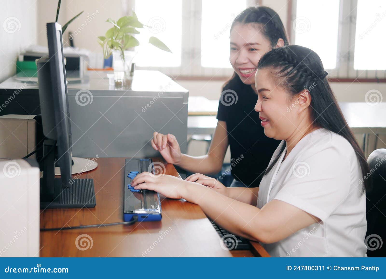 happy asian women co-workers in office workplace including person with blindness disability using computer with refreshable