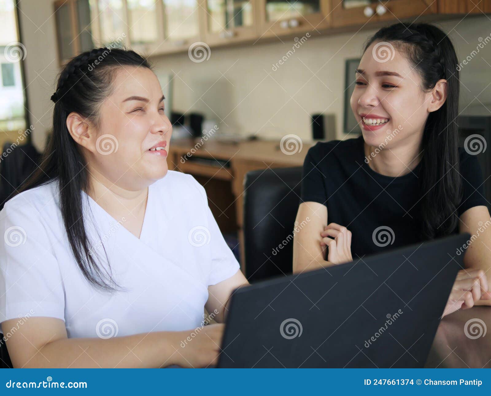 happy asian women co-workers in workplace including person with blindness disability using laptop computer with screen reader