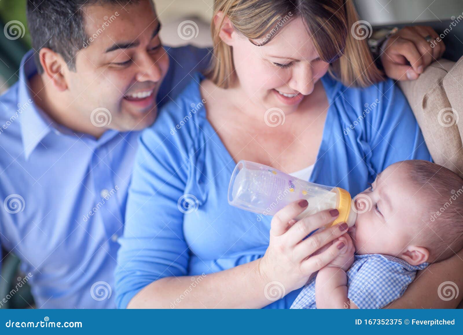 happy attractive mixed race couple bottle feeding their baby