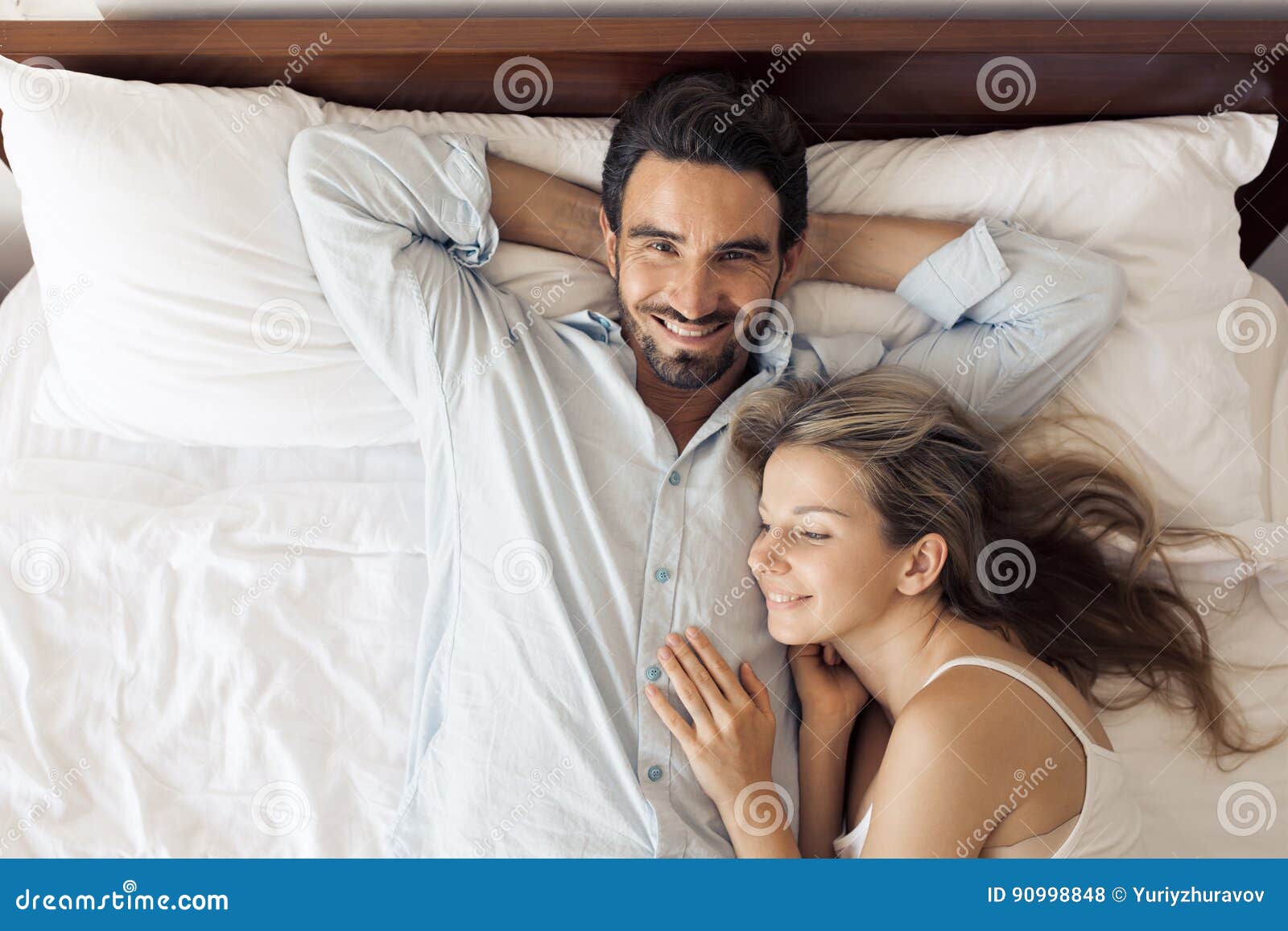 Happy Attractive Smiling Couple Lying on Bed in Bedroom Stock Photo