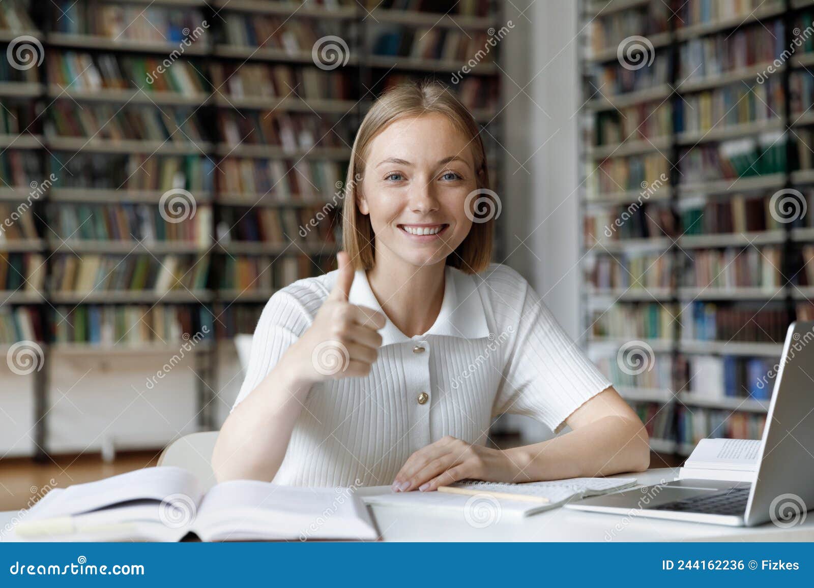Happy Attractive Student Girl Sit in Library Showing Thumbs Up Stock ... photo