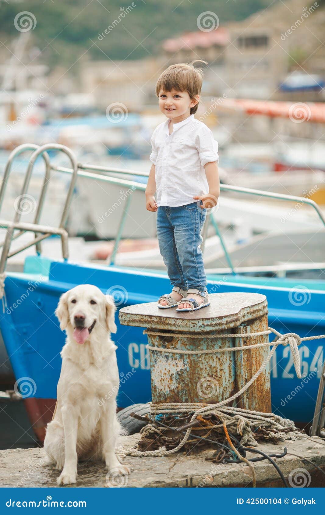 Happy baby boy with him dog on berth in summer. Happy little boy plays at the dock with his dog Labrador