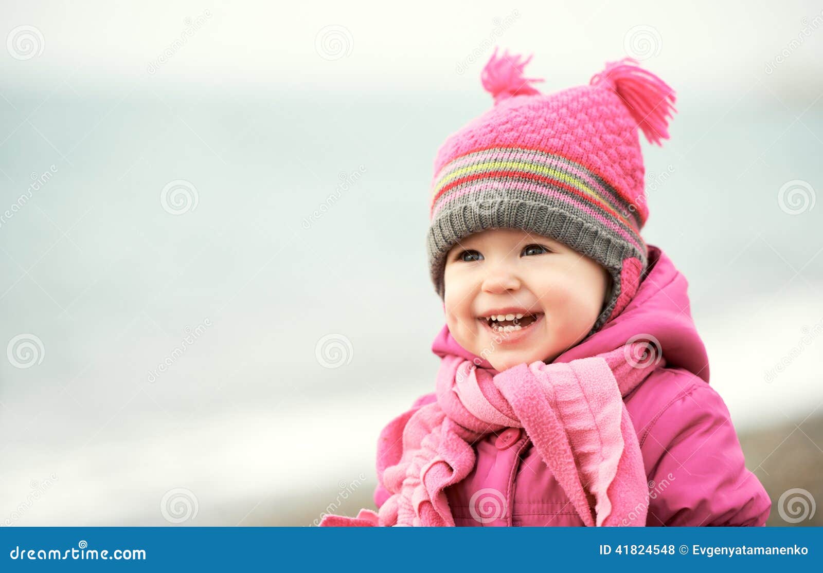 happy baby girl in pink hat and scarf laughs