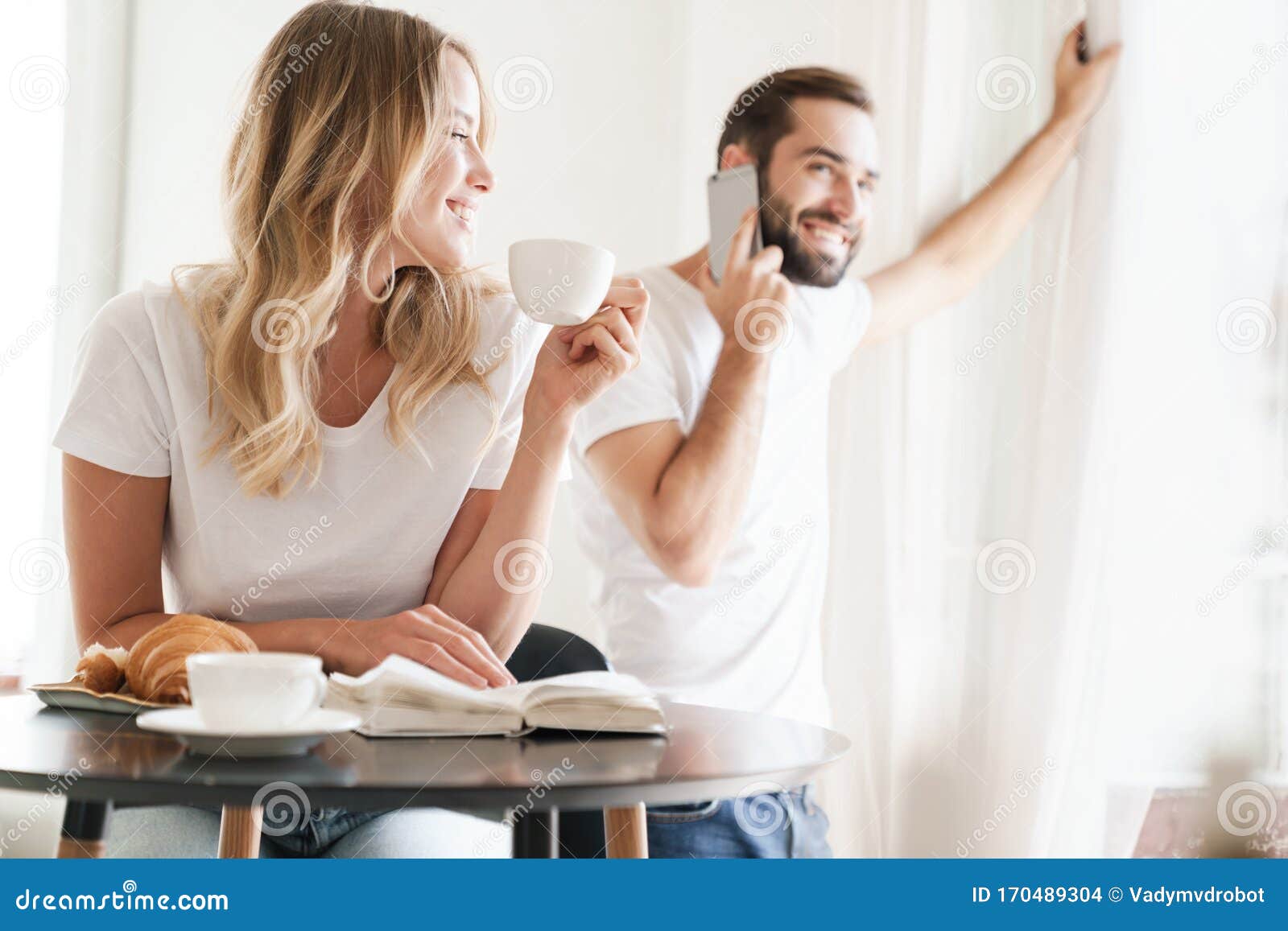 Happy Beautiful Young Couple Having Breakfast at the Kitchen Table