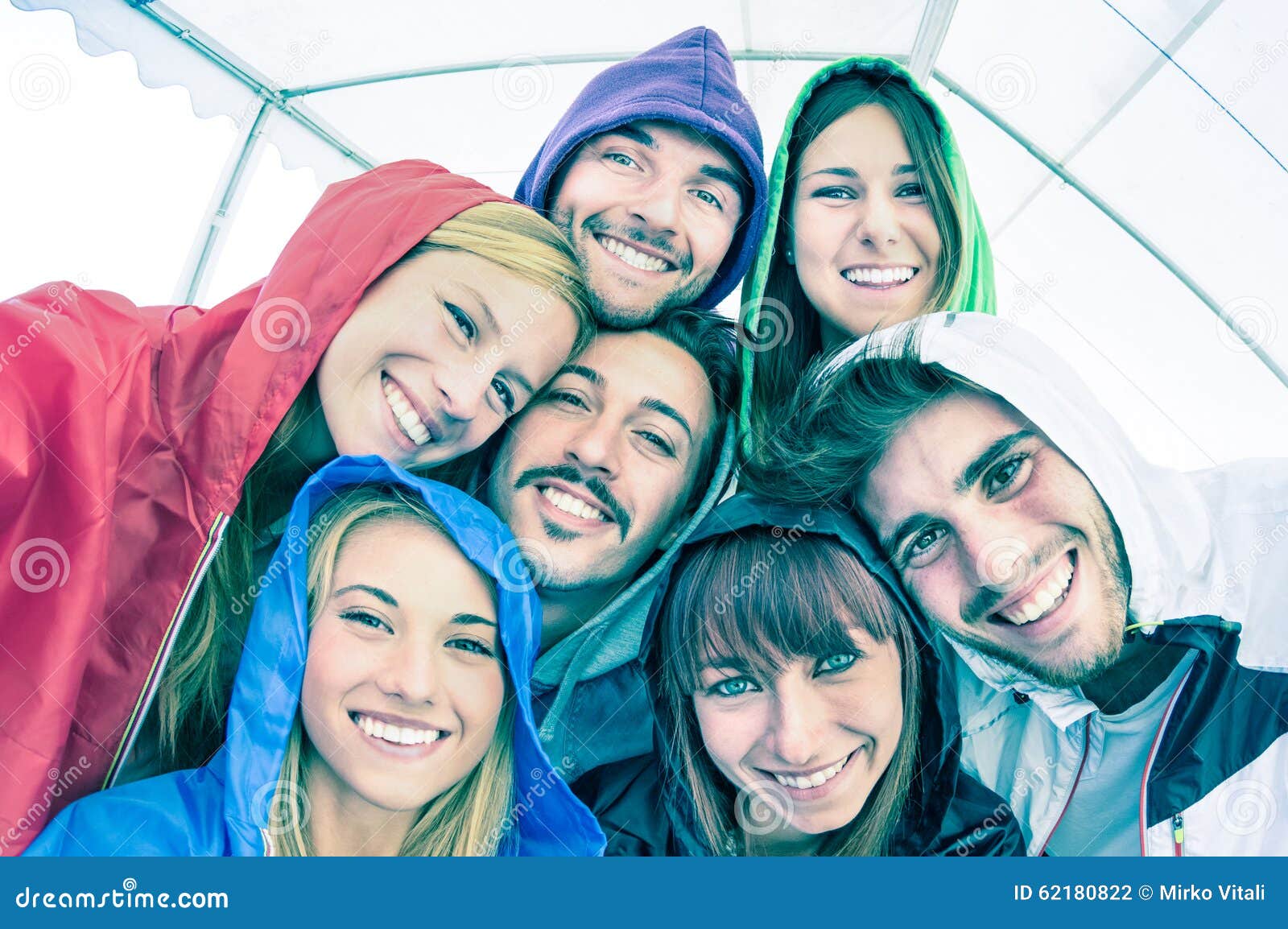 happy best friends taking selfie wearing hoodies outdoors