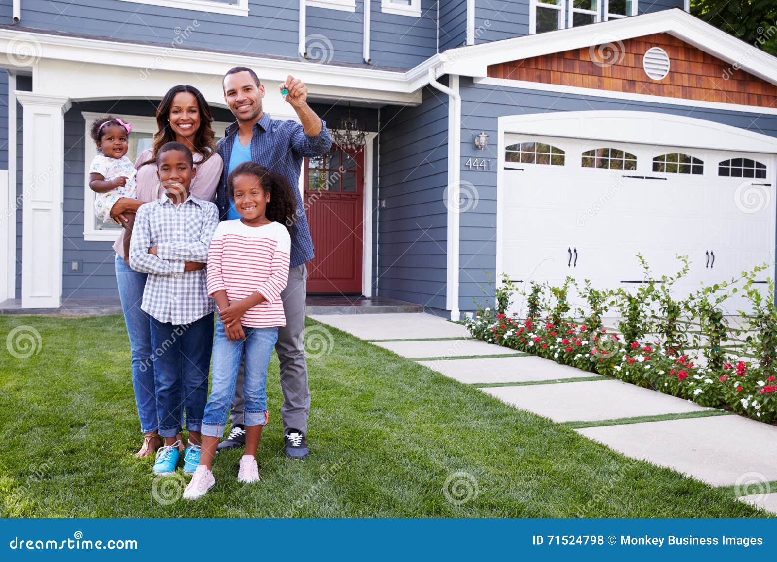 happy black family standing outside their house, dad holding the key