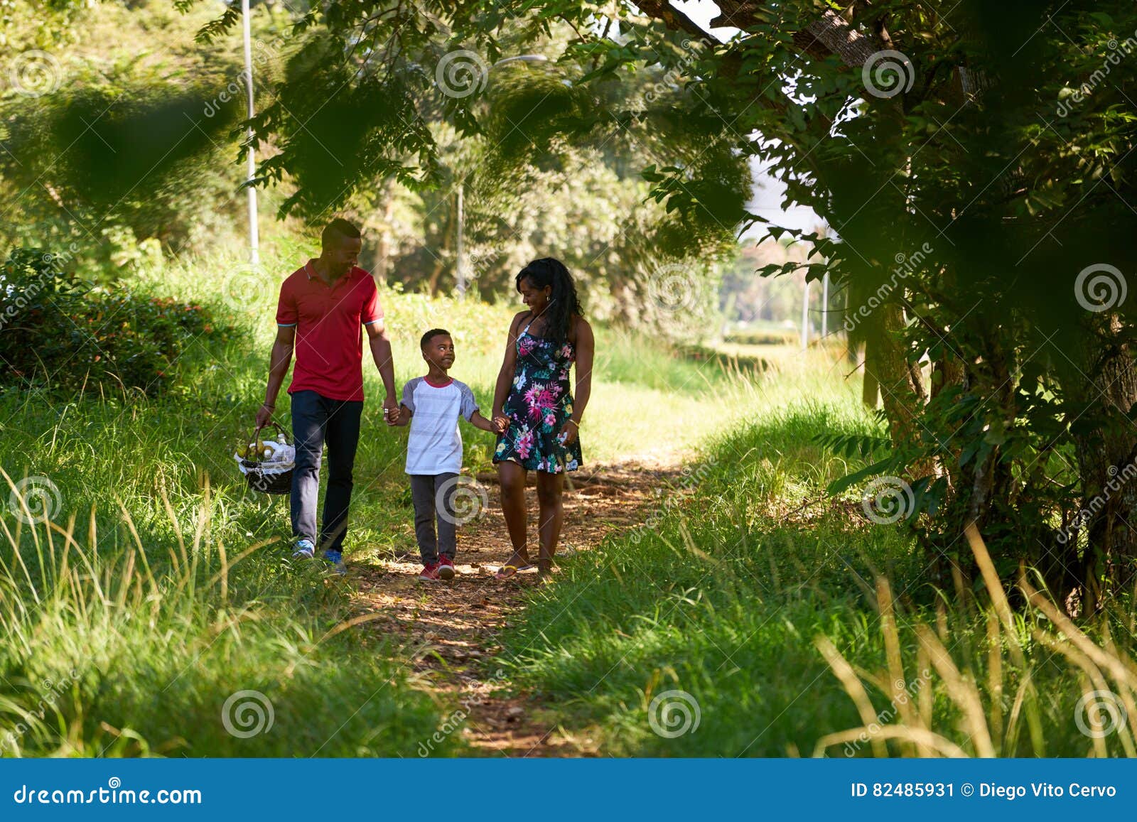 happy black family walking in city park with picnic basket