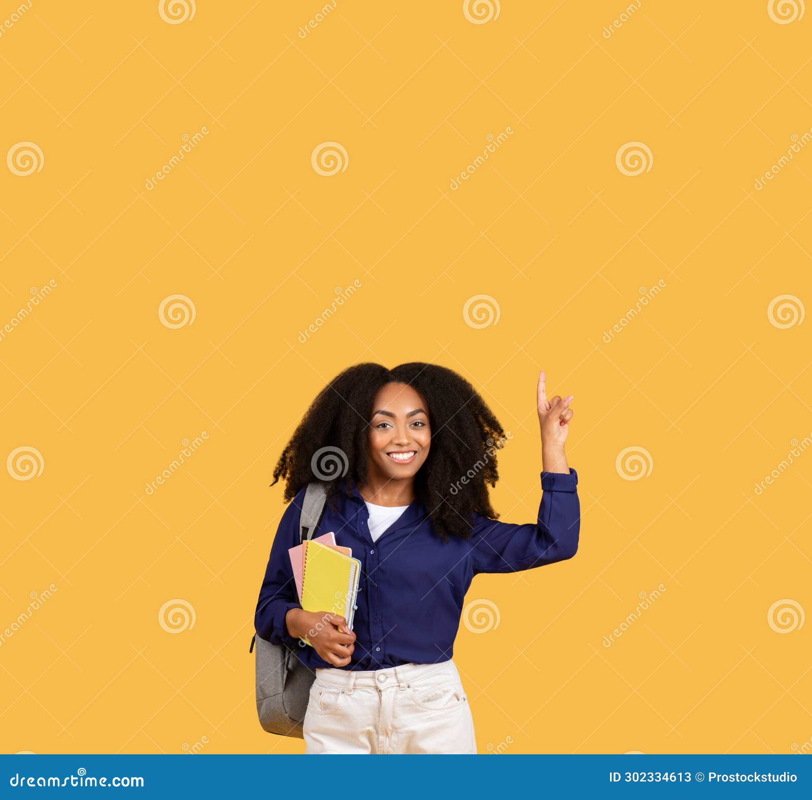 happy black lady student with backpack and copybooks, pointing upwards at free space, on yellow background