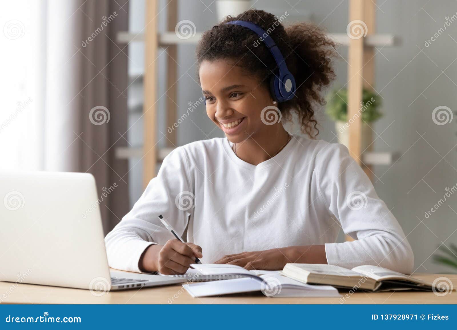 happy black pupil in headphones doing school homework