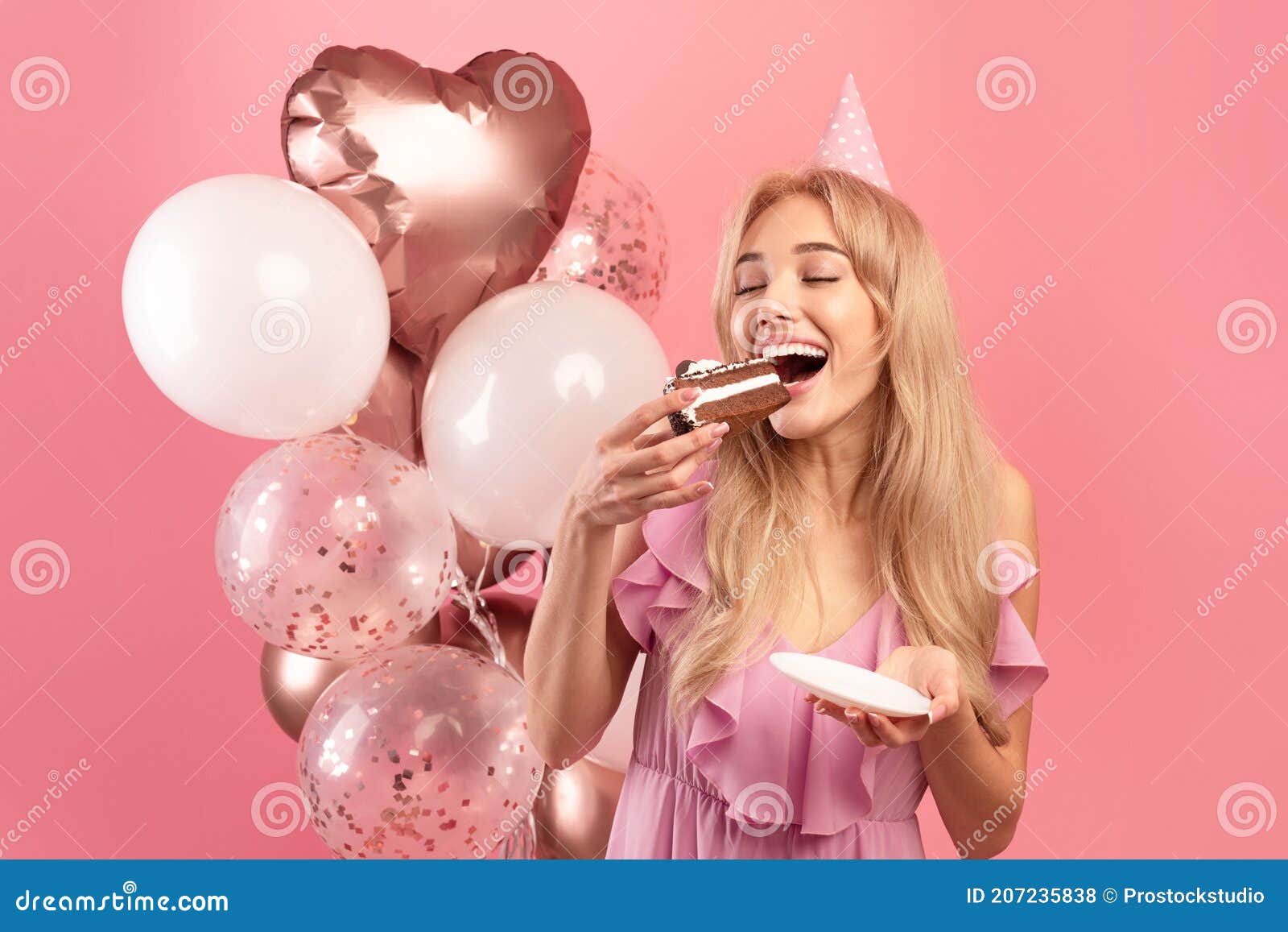 Happy Blonde Woman in Party Hat Eating Piece of Birthday Cake on Pink ...