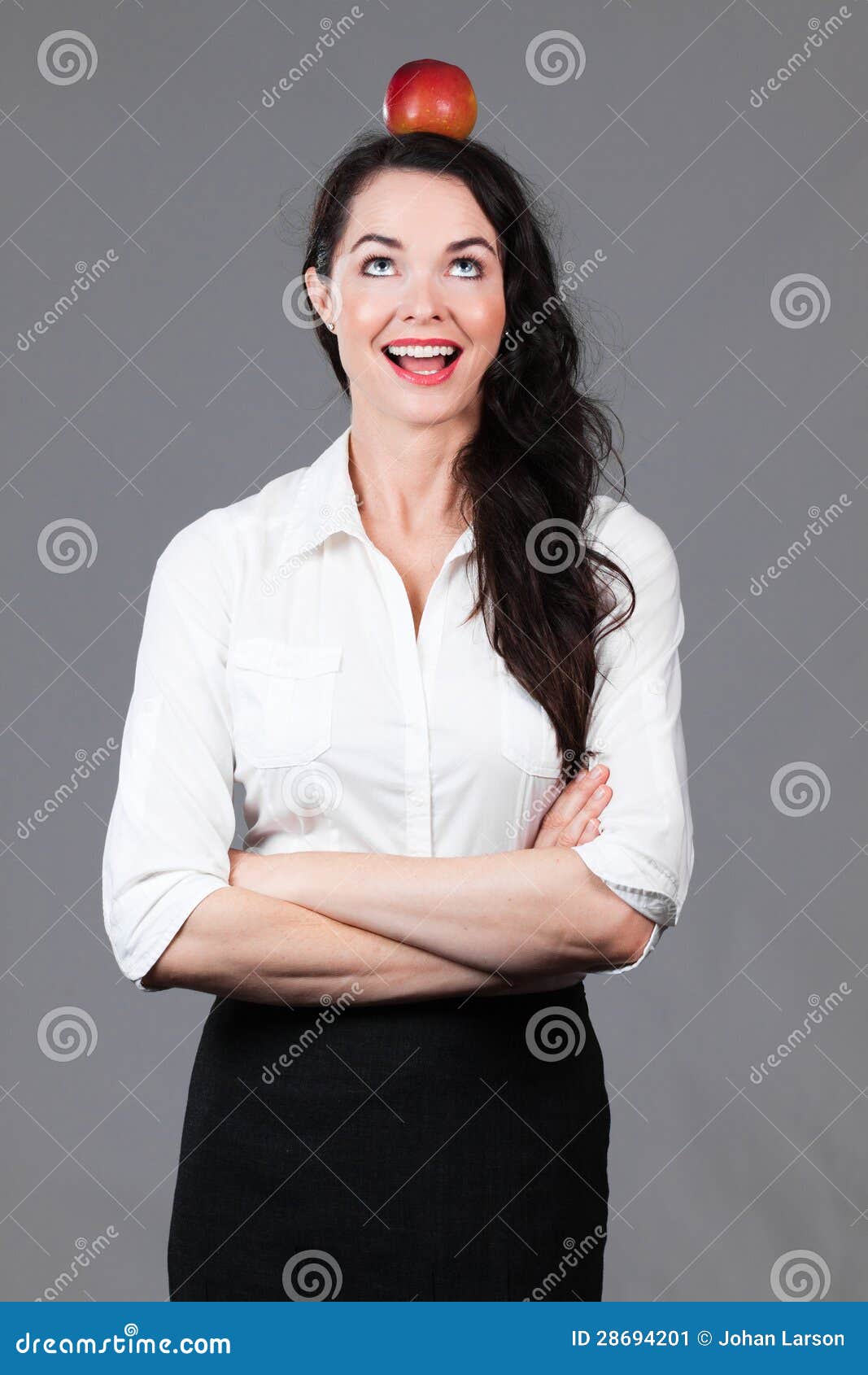 Happy business woman with apple on head. A happy young beautiful business woman smiling with apple on her head.