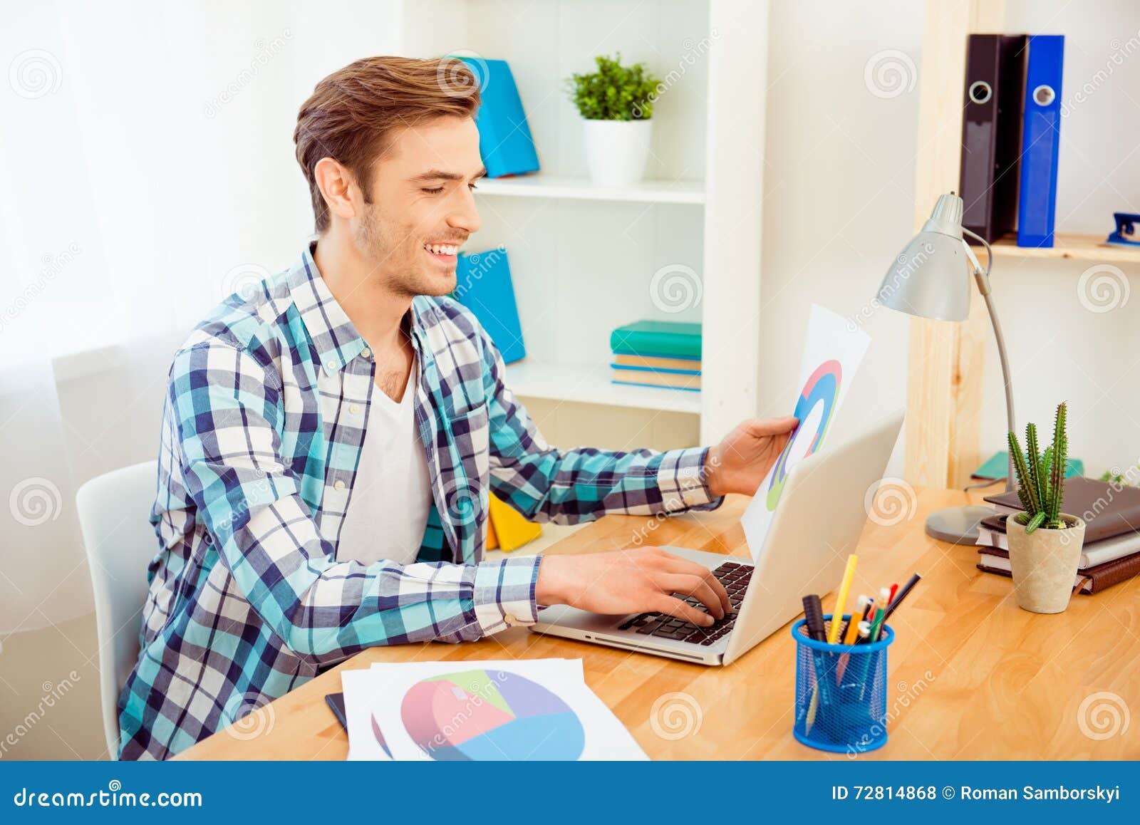 happy businessman holding paper with diagrama and using laptop